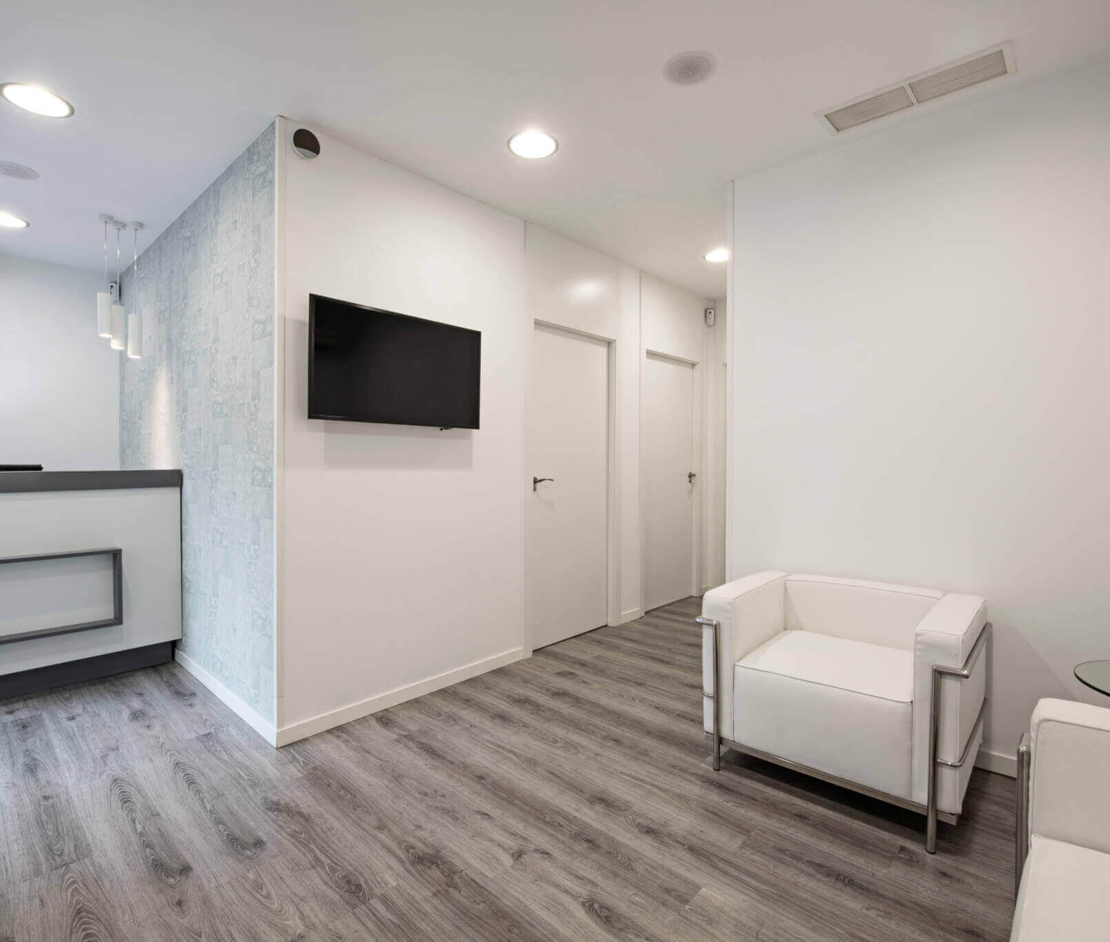Waiting Room In A Clinic With Tv, White Walls And Sofas And Gray